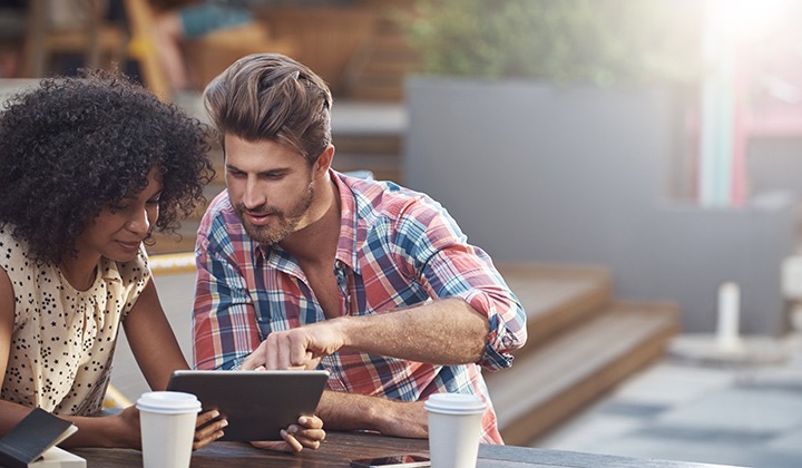 Two people using tablet in outdoor setting