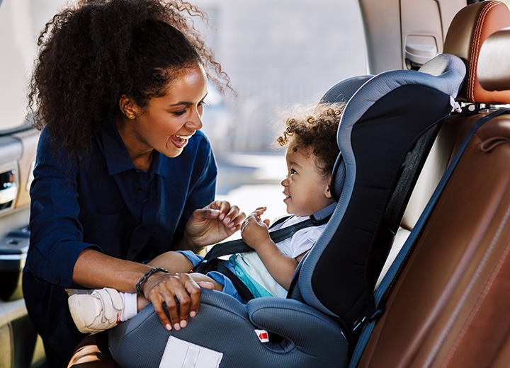 Mother securing daughter in carseat