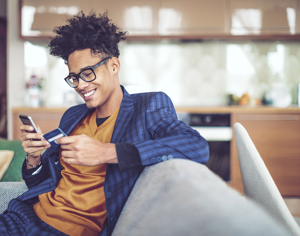 Young man using debit card and phone