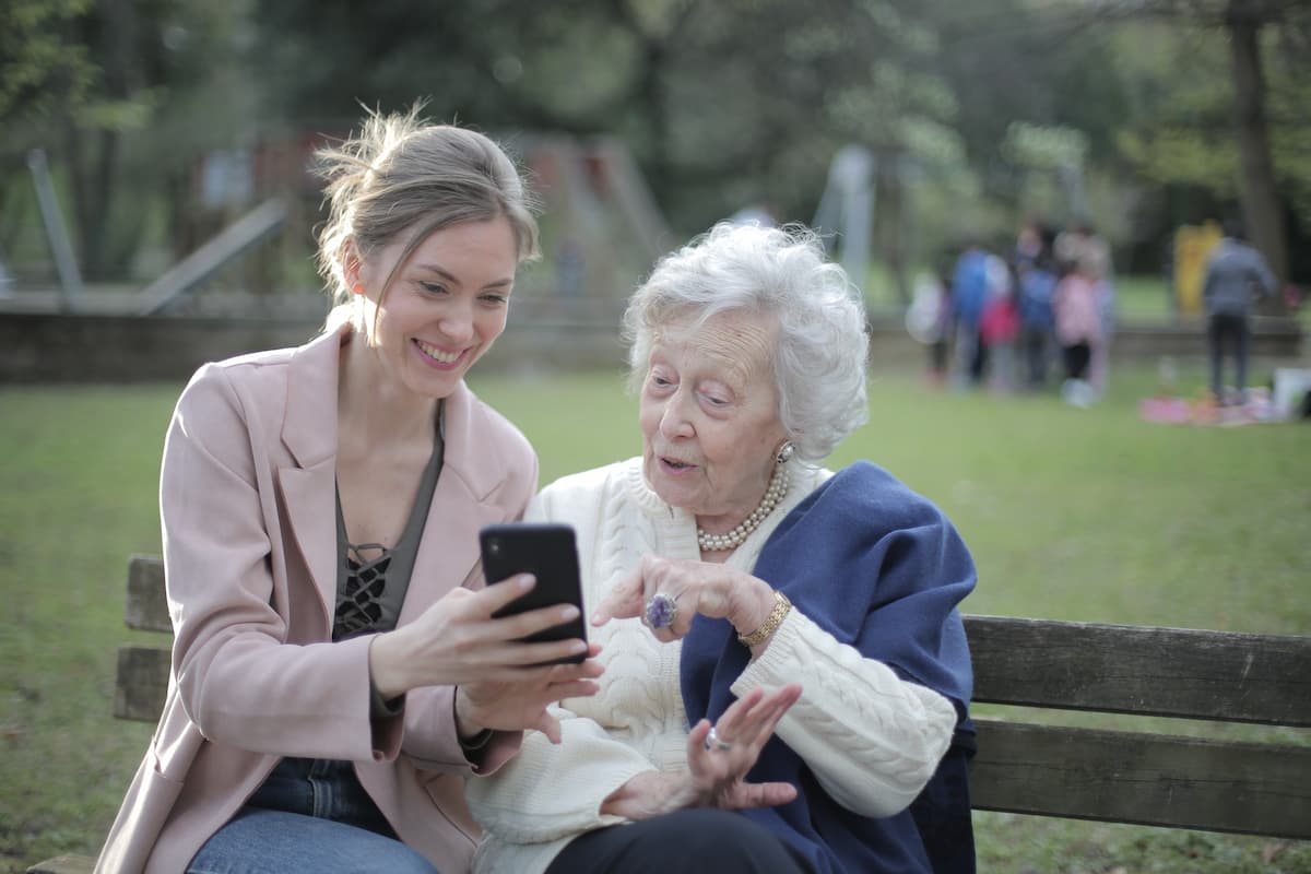 girl showing elderly woman a cellphone. 