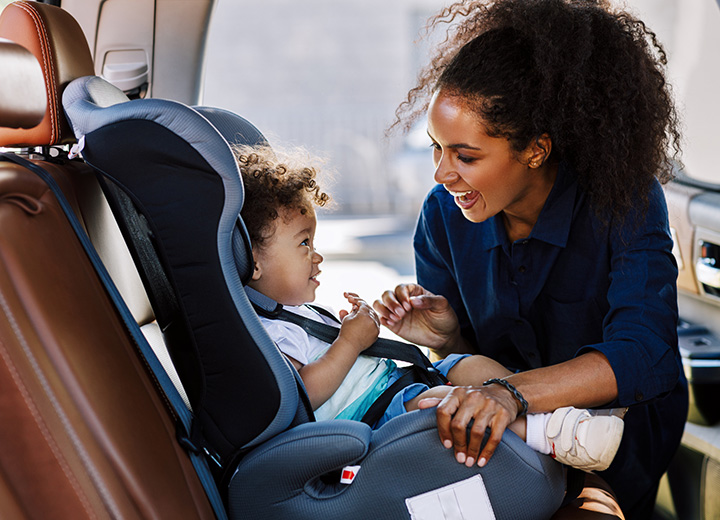 Mother securing daughter in carseat