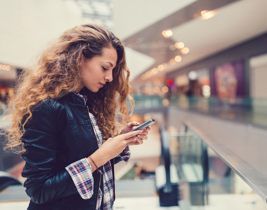 Woman using phone in mall