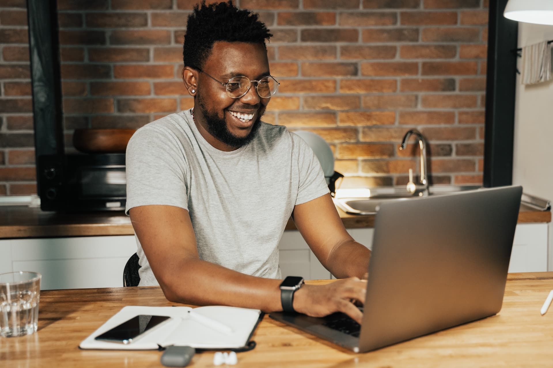 Smiling man looking at laptop in kitchen.