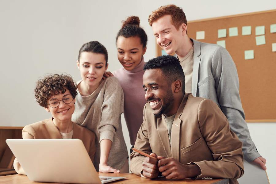 Group of people at desk looking at laptop.