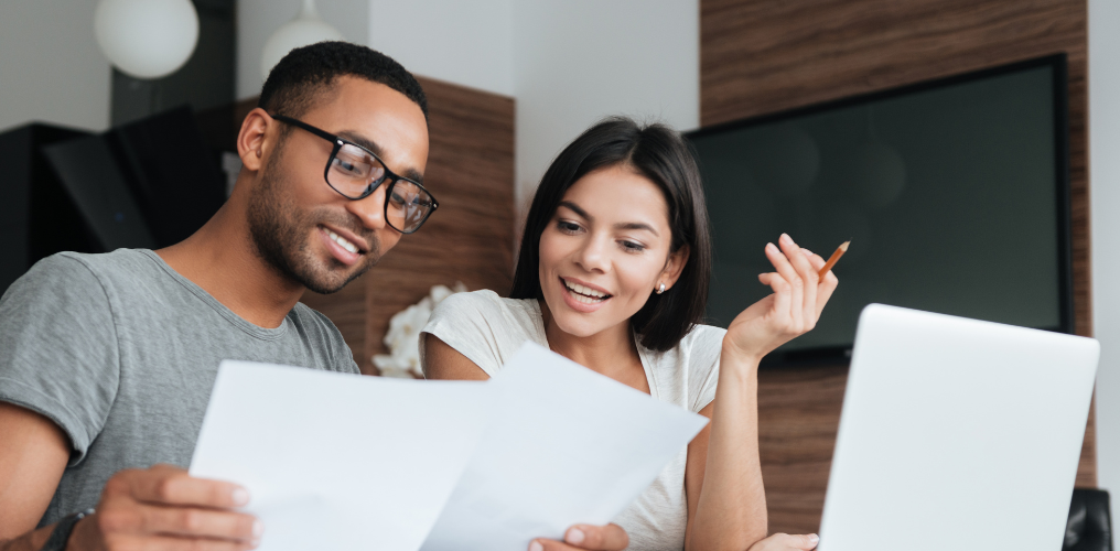 Man and woman smiling looking at papers. 