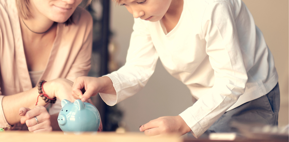 Kid putting money into piggy bank. 