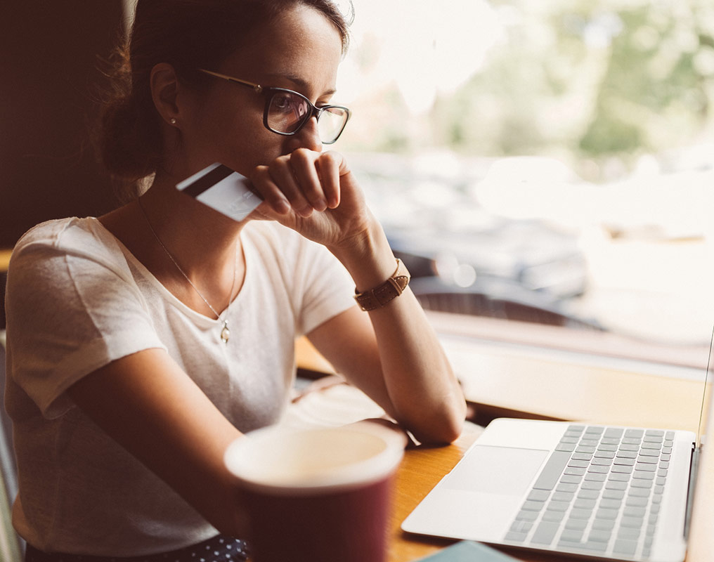 Young woman using debit card on computer