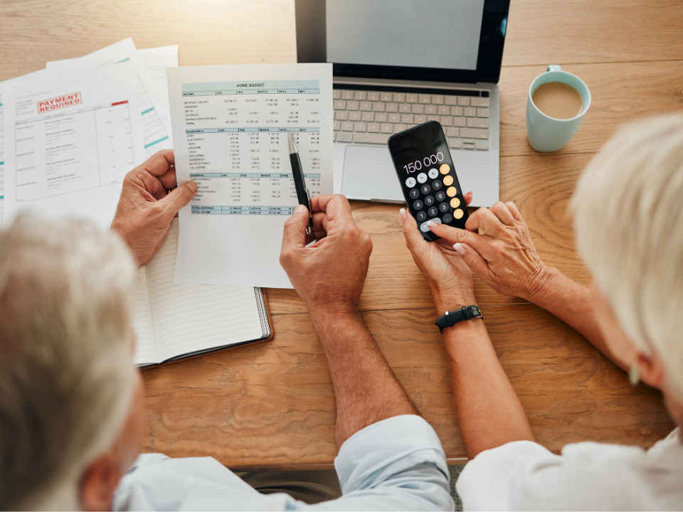 Senior couple calculating finances with paper on table in the background. 