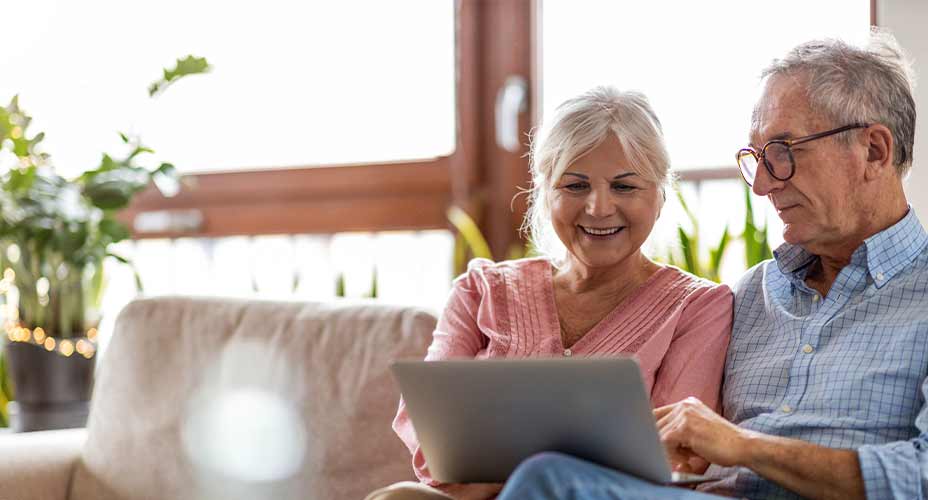 mature couple sitting on couch looking at computer