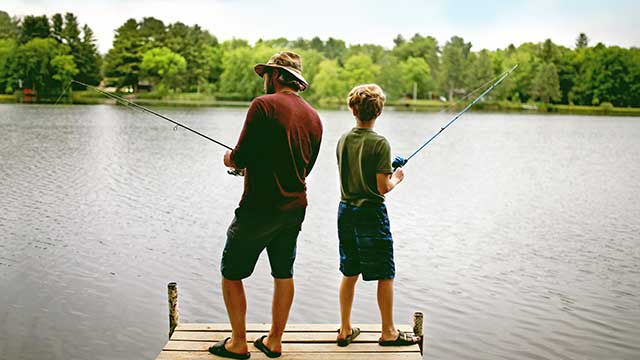 father and son fishing in pond