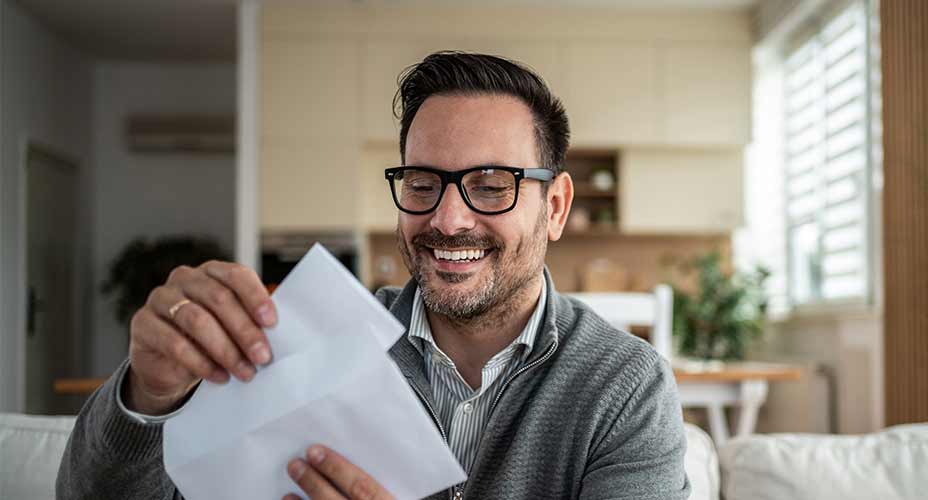 Man opening mail in living room smiling