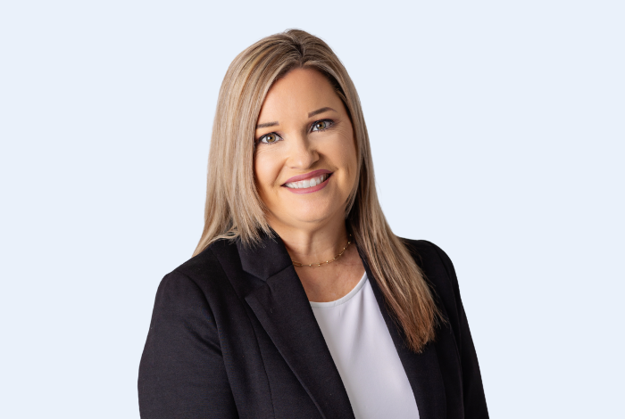 Traci Sedlacek, Vision Bank Prague branch manager, headshot on blue background. 